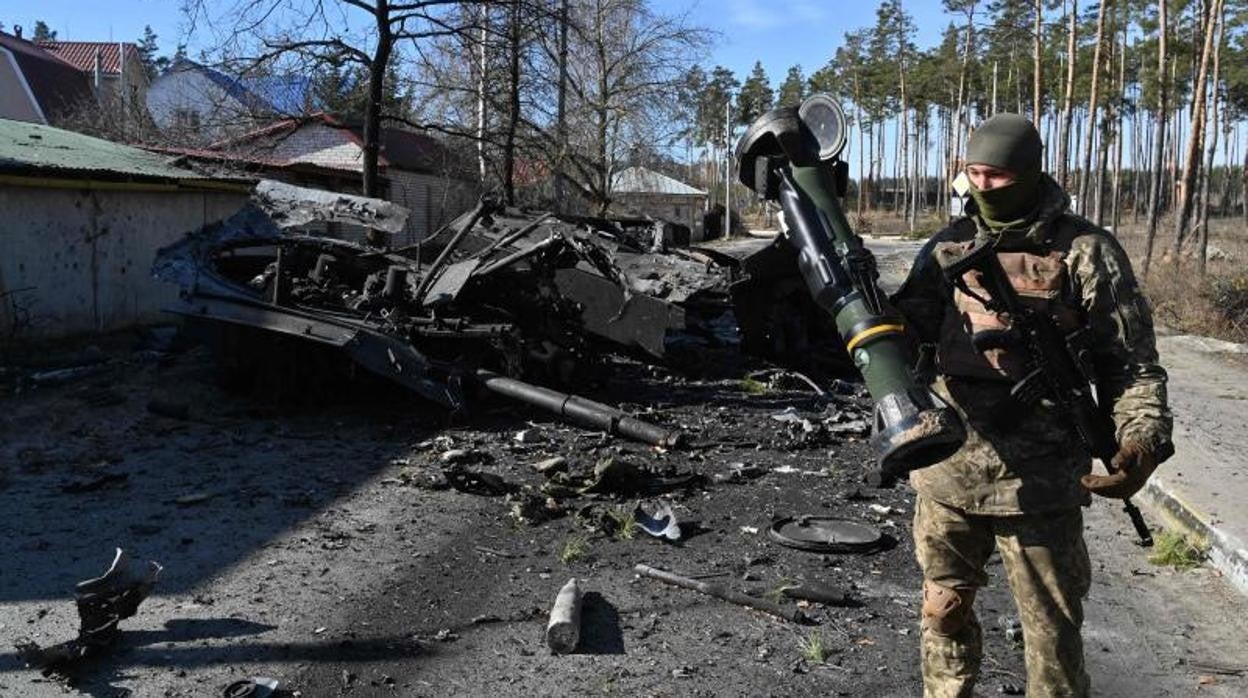 Un soldado ucraniano porta un misil anticarro NLAW, una de las armas más efectivas para Ucrania en Irpin, al norte de Kiev . Al lado un vehículo blindado ruso utilizado para transportar soldados