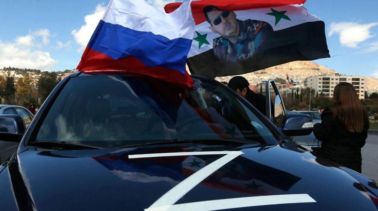 Los sirios ondean la bandera de Rusia y un retrato del presidente Bashar al-Assad durante una manifestación en apoyo de Rusia en la capital siria, Damasco