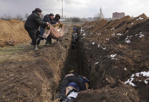 Un grupo de personas arroja cuerpos a una fosa común de Mariúpol