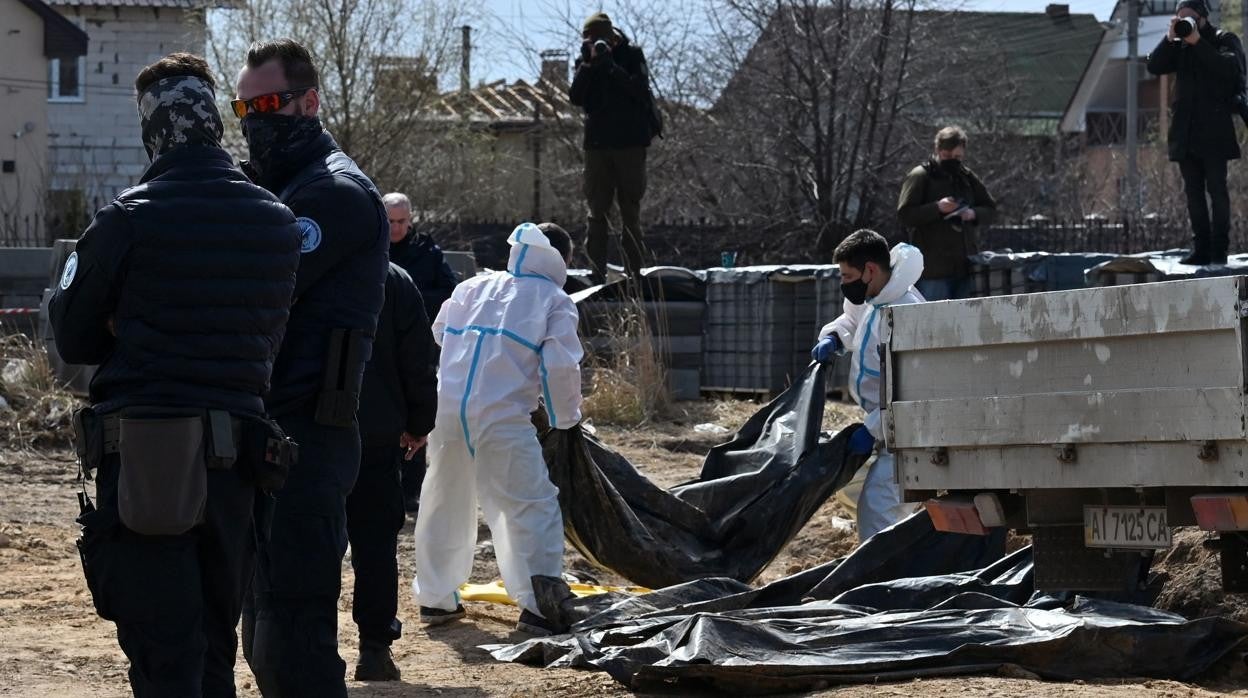 Trabajadores transportan bolsas para cadáveres de una fosa común en la ciudad ucraniana de Bucha