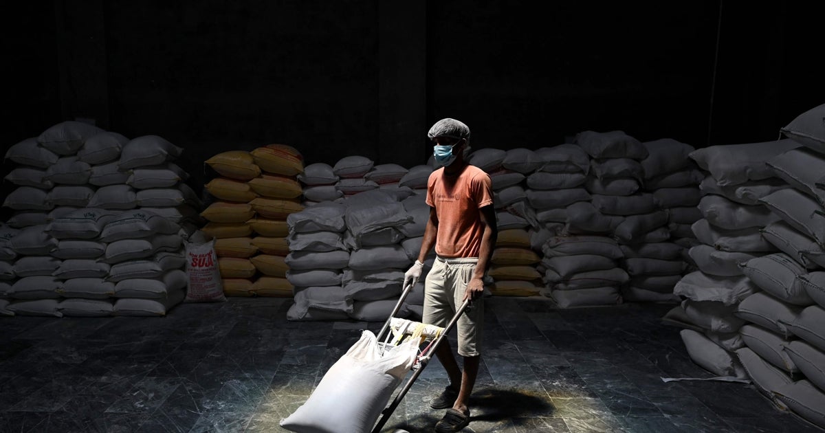 Un hombre transporta un saco de harina de trigo en un almacén de Khanna, en la India, cuyas autoridades han prohibido la exportación de este cereal, lo que agravará la escasez mundial