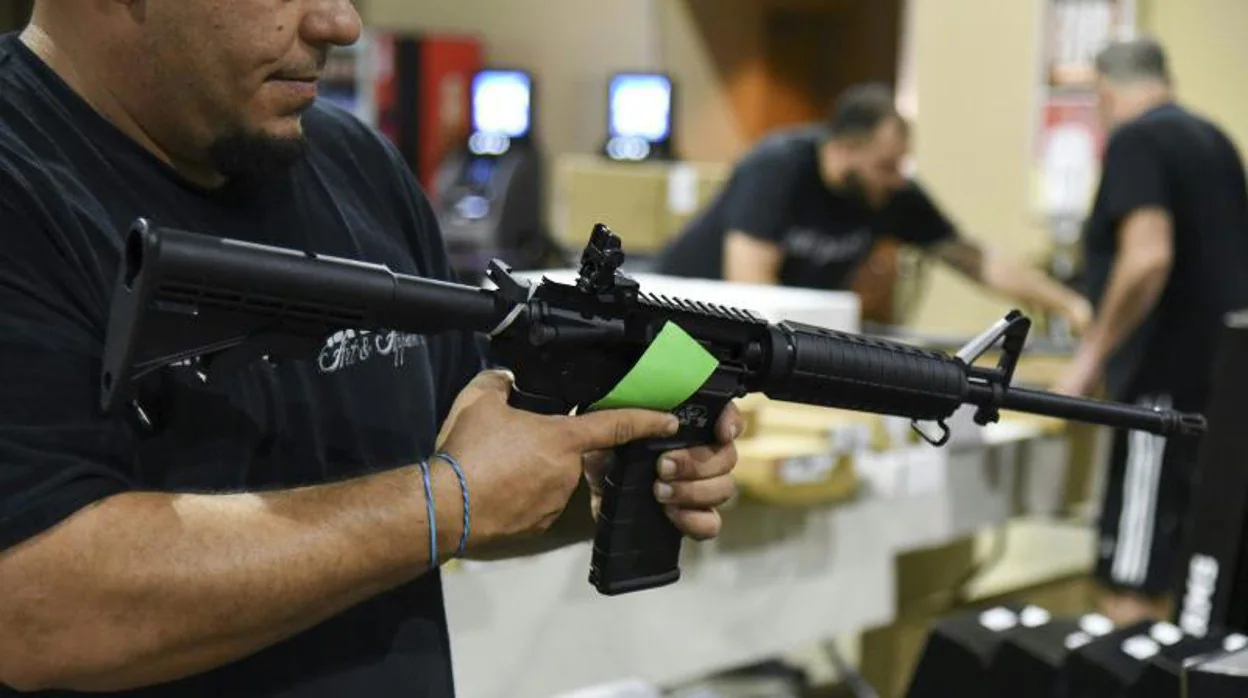 Un hombre porta un fusil AR-15 en una tienda de armas en Miami, Florida
