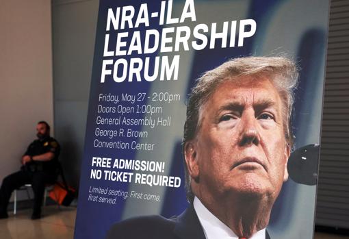 Un cartel muestra la cara del expresidente Trump en la Convención Nacional del Rifle