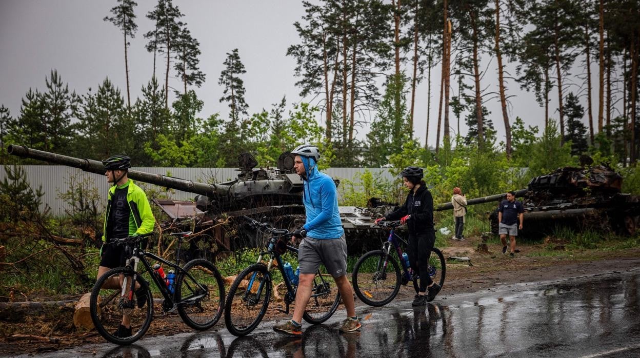 Ciclistas pasan cerca de un tanquero ruso a las afueras de Kiev
