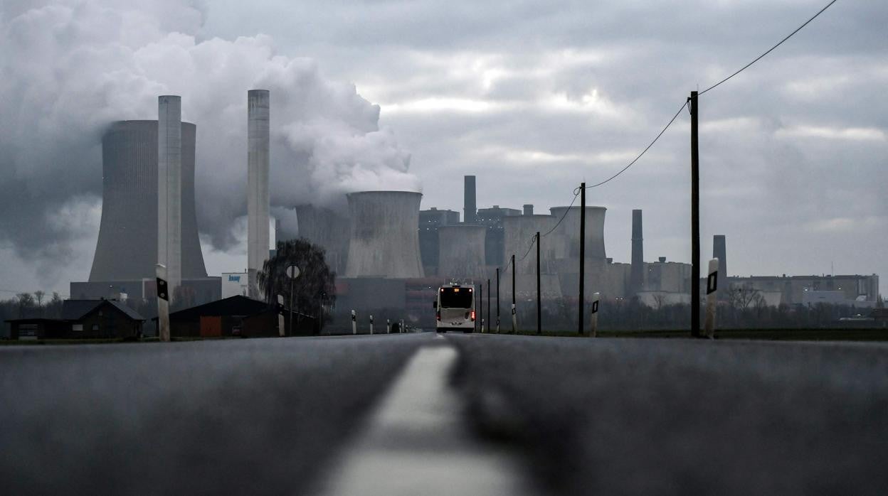 Un autobús conduce por una carretera mientras el vapor se eleva desde las torres de enfriamiento de la planta de energía alimentada con lignito del gigante energético alemán RWE en Niederaussem (Alemania)