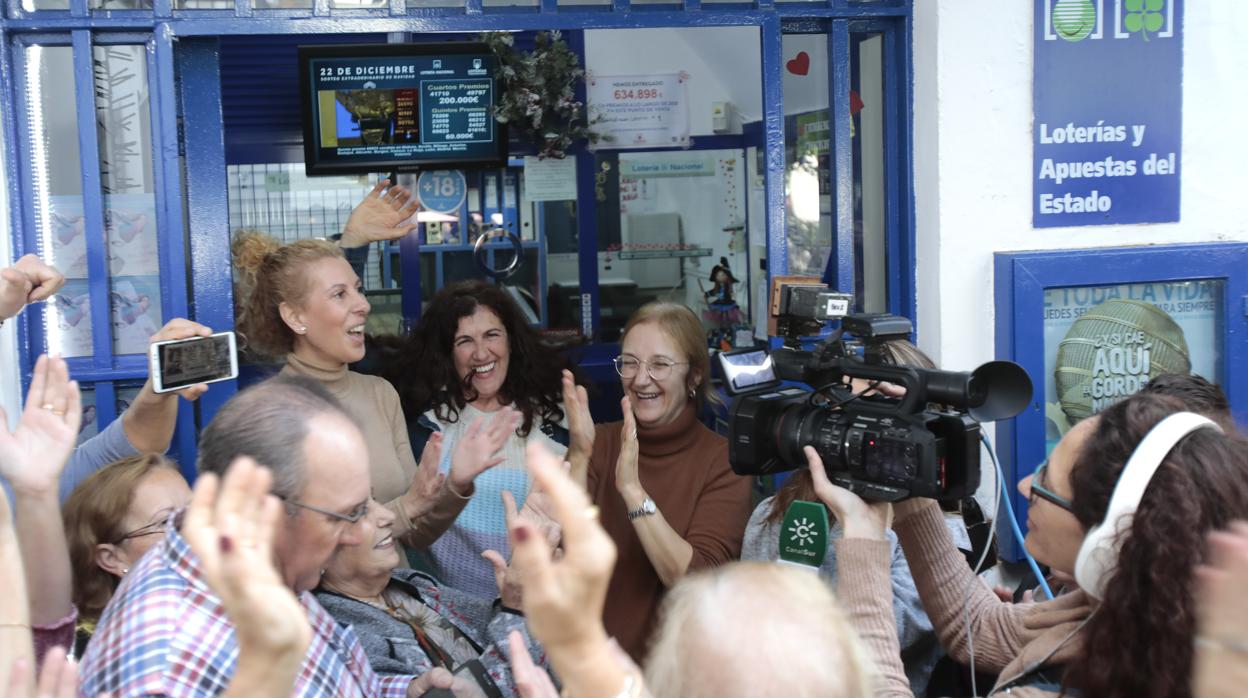 Fotografía de archivo de un grupo de personas celebrando el cuarto premio de la Lotería de Navidad de 2019 a las puertas de la administración que vendió el número, en Utrera (Sevilla)