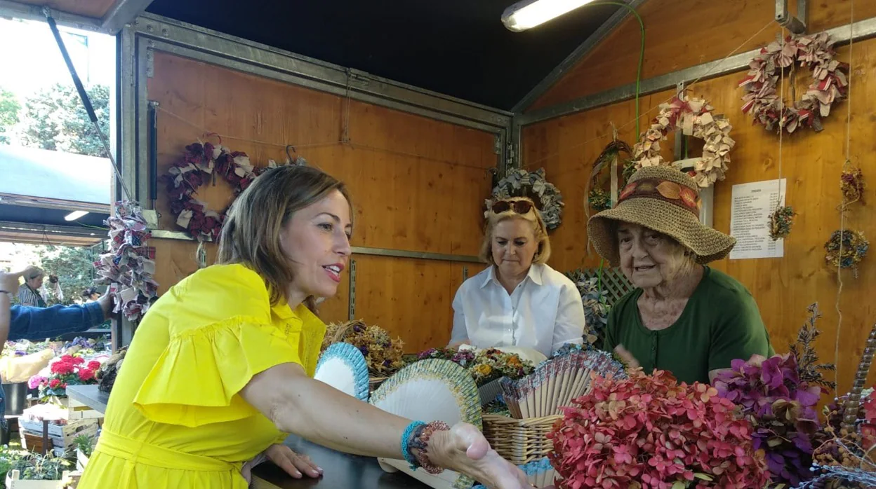 Natalia Chueca, consejera de Servicios Públicos y Movilidad del Ayuntamiento de Zaragoza, conversa con una asociacion de mujeres que realiza centros florales para apoyar a colectivos vulnerables