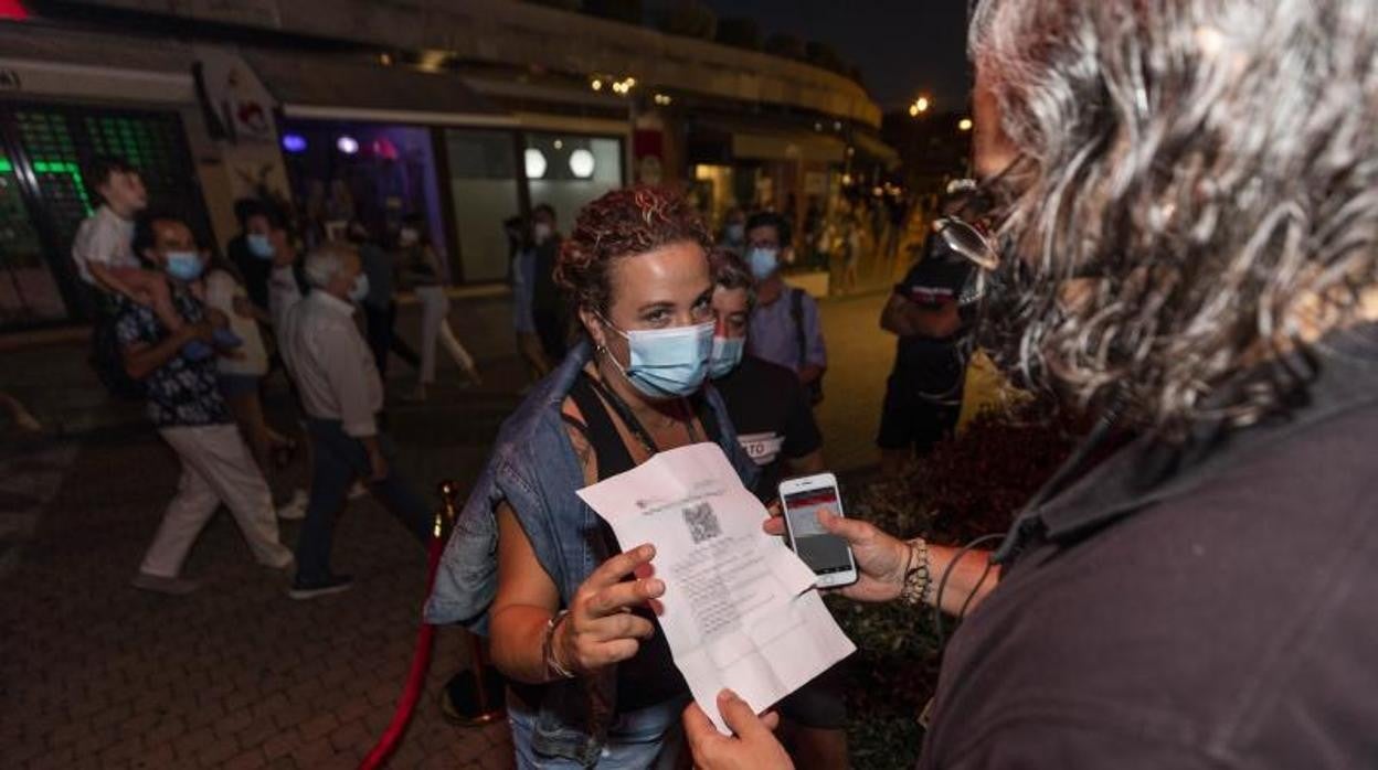 Una mujer muestra un certificado con sus vacunas contra el COVID-19 en regla para acceder a un local en Sanxenxo