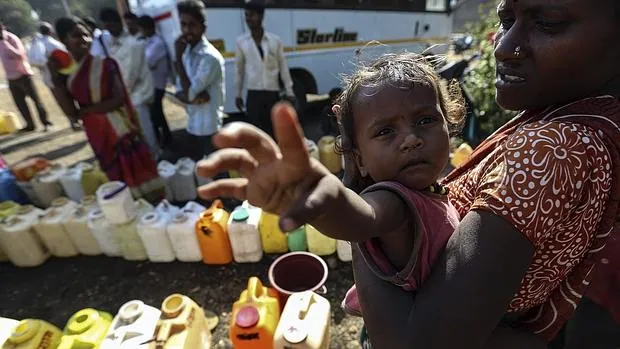Granjeros y agricultores recolectan agua cerca de un campo de refugiados temporal de Bombay, India,