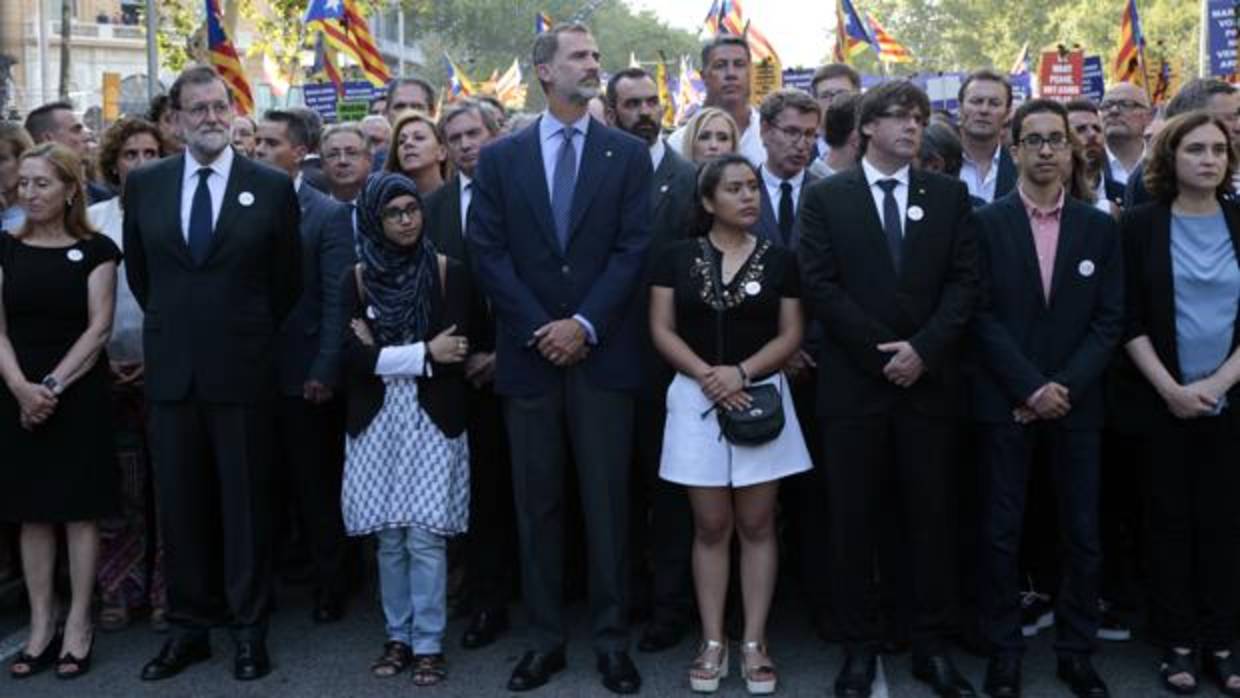 El Rey, flanqueado por dos mujeres, junto a Mariano Rajoy y Carles Puigdemont, encabezaron la manifestación del sábado en Barcelona