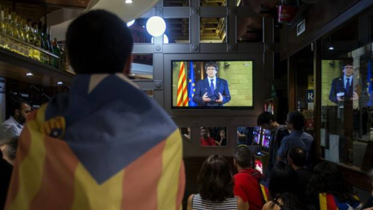 Unos ciudadanos siguen desde la televisión la declaración institucional del presidente de la Generalitat