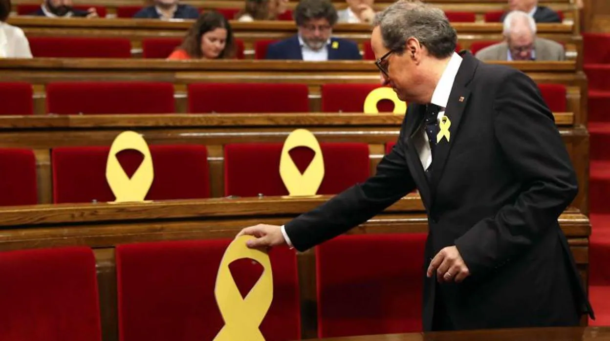 El presidente de la Generalitat, Quim Torra, coloca un lazo amarillo en el Parlament