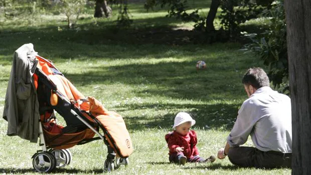 Un padre juega con su bebé en el parque de El Retiro, en Madrid