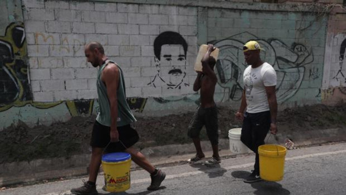 Personas recogen agua este lunes, en la autopista Francisco Fajardo, en Caracas