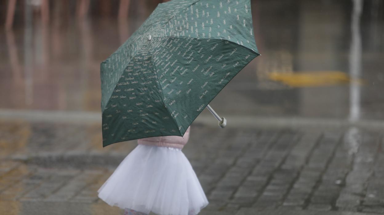 Una niña se resguarda de la lluvia en la Plaza de San Juan Dios