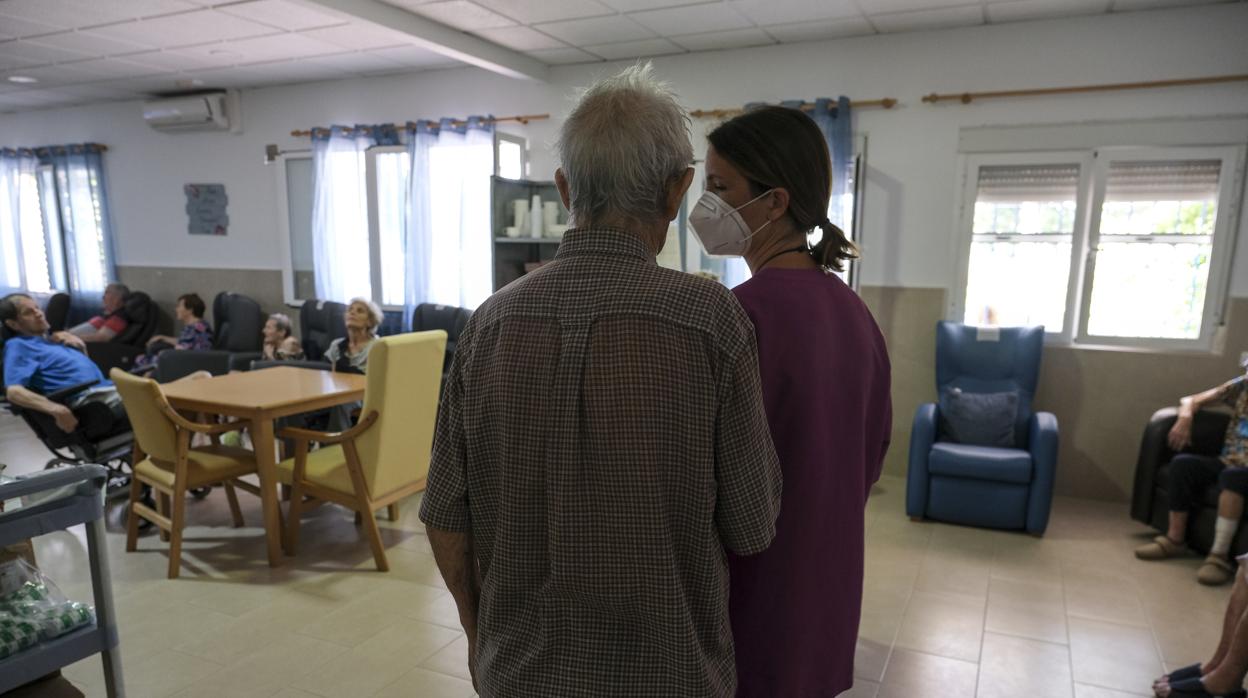 Una trabajadora junto a un anciano, en una residencia.