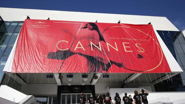 Trabajadores colocan el póster oficial del Festival de Cine de Cannes, que se celebra entre el 17 y el 28 de mayo