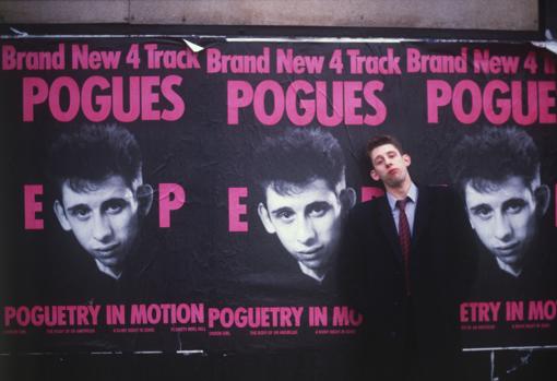 Shane MacGowan frente a unos carteles publicitarios, en sus años de juventud