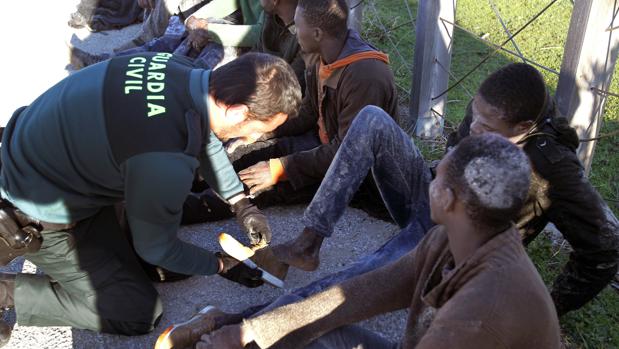 Un agente ayuda a poner un zapato a uno de los once inmigrantes que han llegado a Bolonia