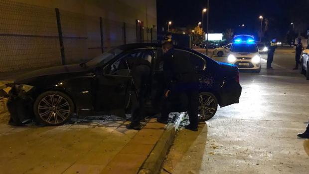 Efectivos policiales indagan en el interior del vehículo estrellado contra un muro vallado de Coria del Río