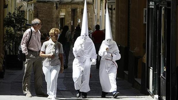 Turistas observan a dos penitentes en Cádiz