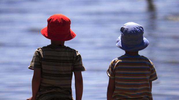 Dos niños, protegidos con gorras en la playa