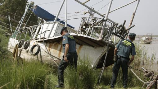 Dos agentes del Seprona revisan un barco angulero que está varado