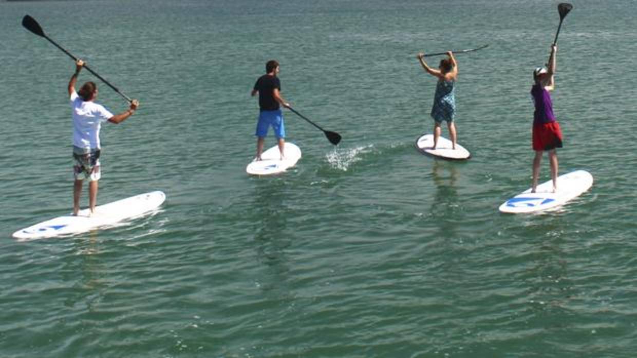 Varias personas practican paddle surf