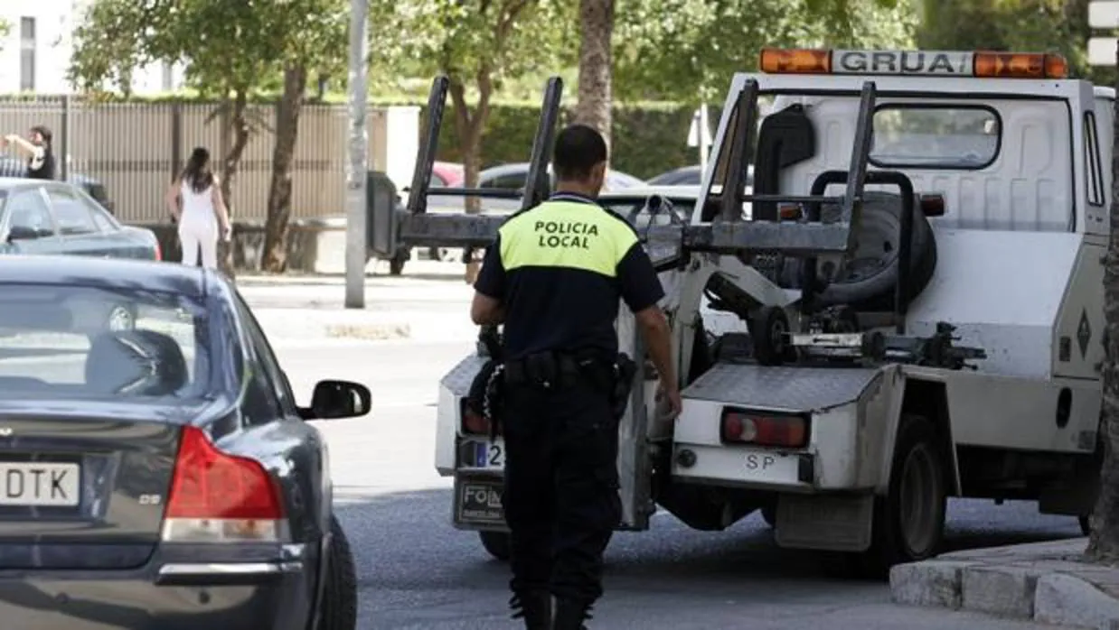 Un agente de Policía Local, a punto de retirar un vehículo con la grúa municipal.