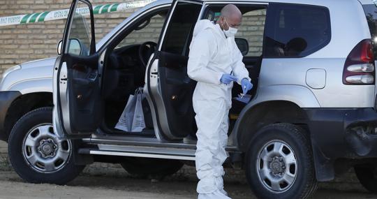 Un agente toma muestra del coche de los ladrones que estaba en la puerta de la finca