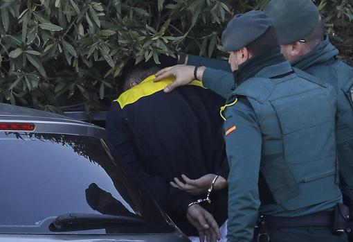 Uno de los detenidos es metido en uno de los coches de la Guardia Civil