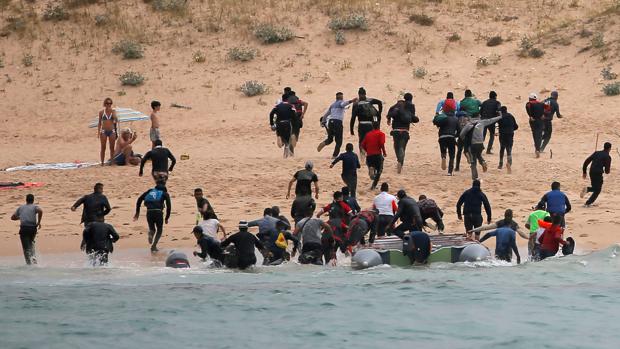 Un grupo de inmigrantes desembarca en una playa de Tarifa ante la mirada de los bañistas