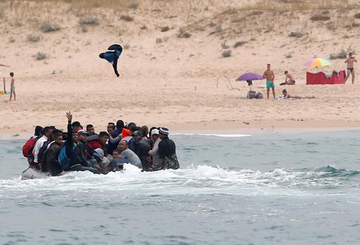 Un grupo de inmigrantes desembarca en una playa de Tarifa ante la mirada de los bañistas