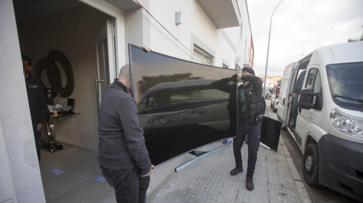 Agentes de la Guardia Civil cargan en el furgón una televisión incautada en la casa de Tejón.