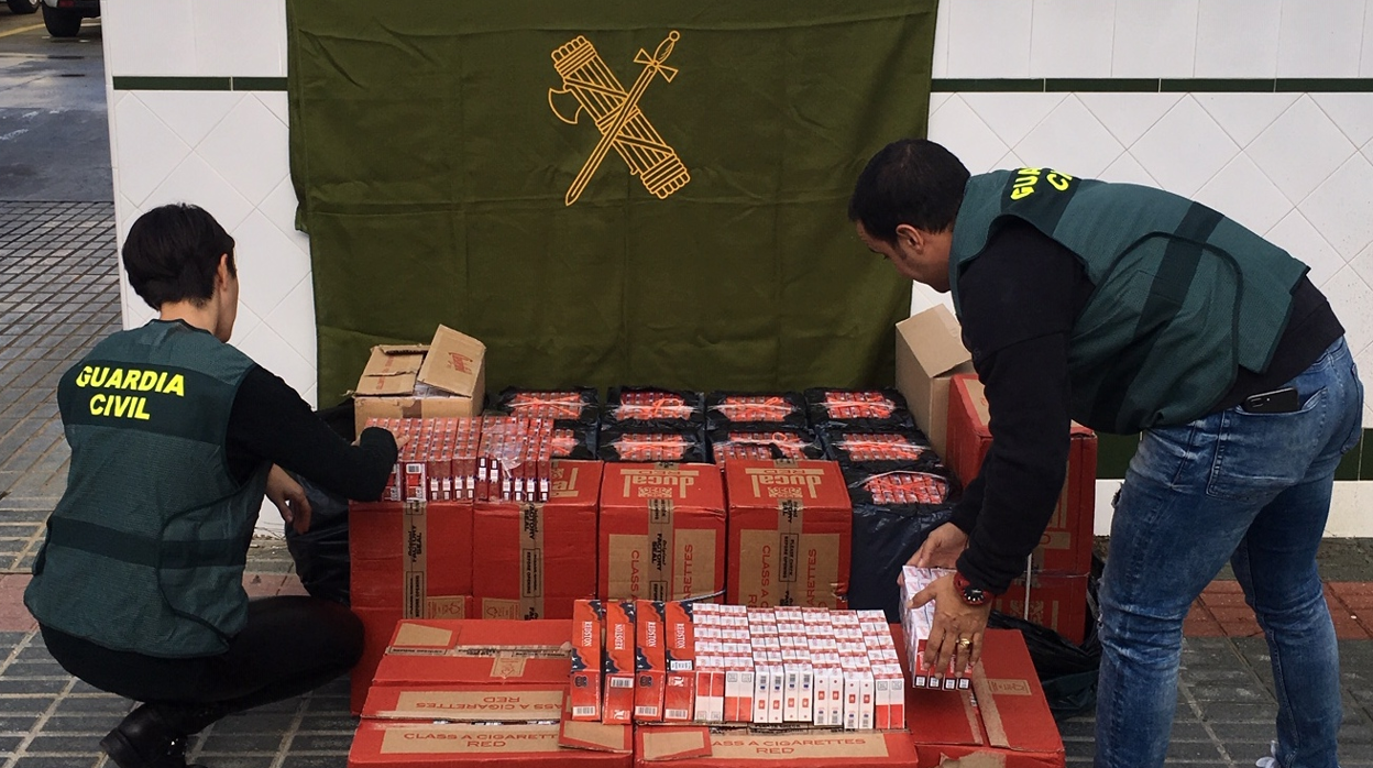 Dos agentes de la Guardia Civil contabilizan las cajetillas de tabaco de contrabando inacutadas a un clan familiar del Aljarafe