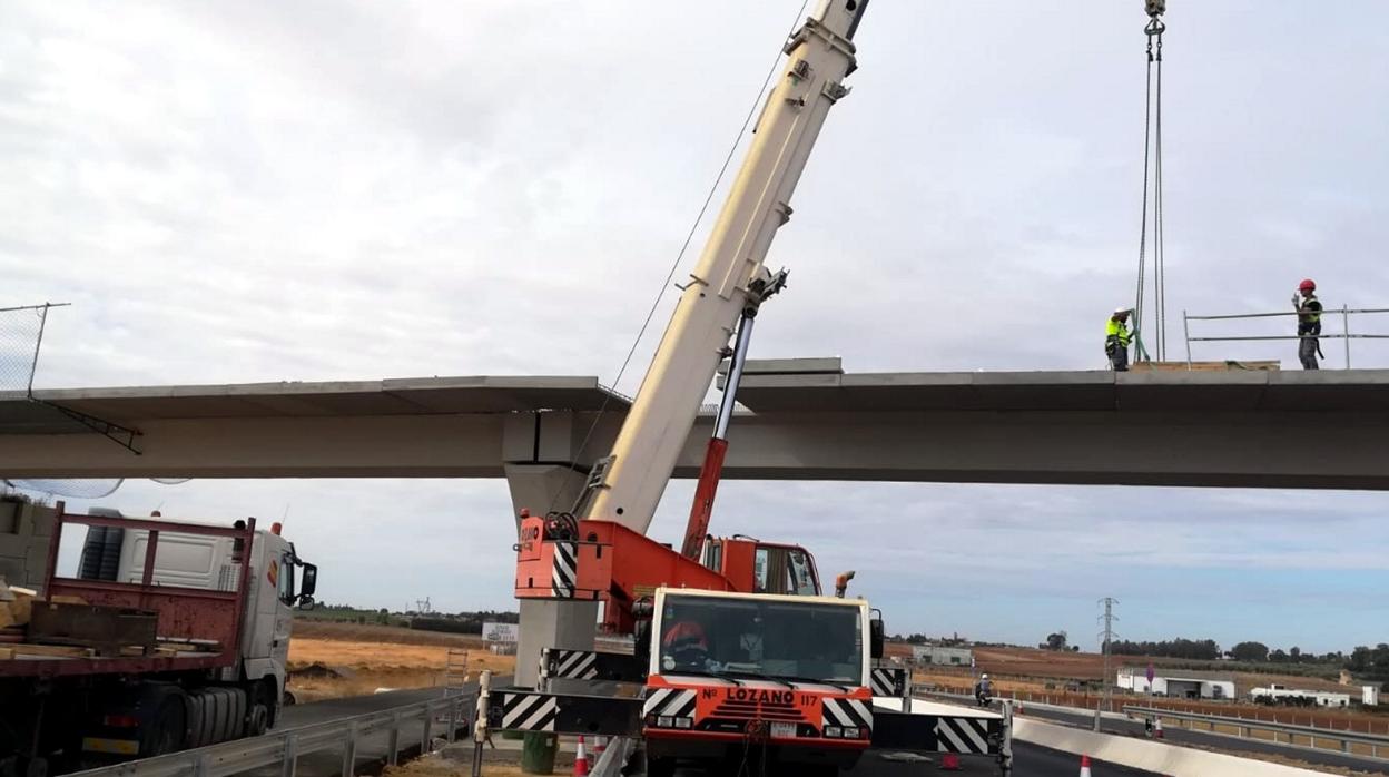 Una grúa de grandes dimensiones trabaja en el montaje del paso elevado en la carretera A-392