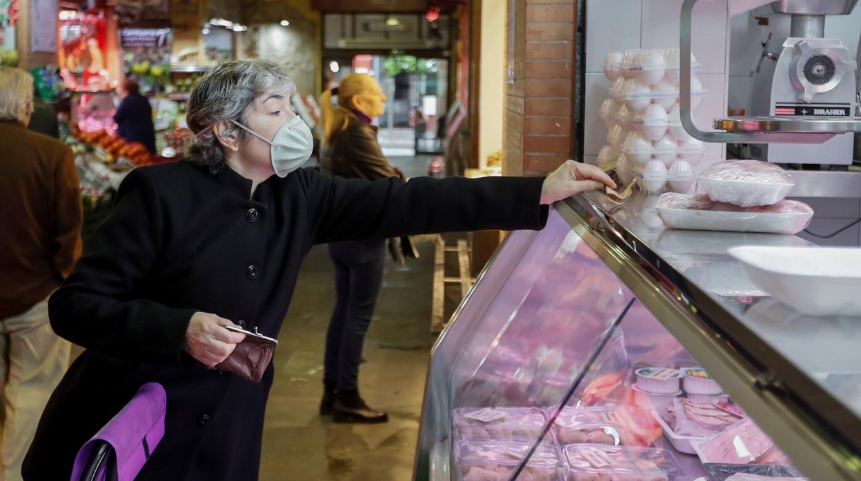 Una mujer realiza la compra en un mercado sevillano