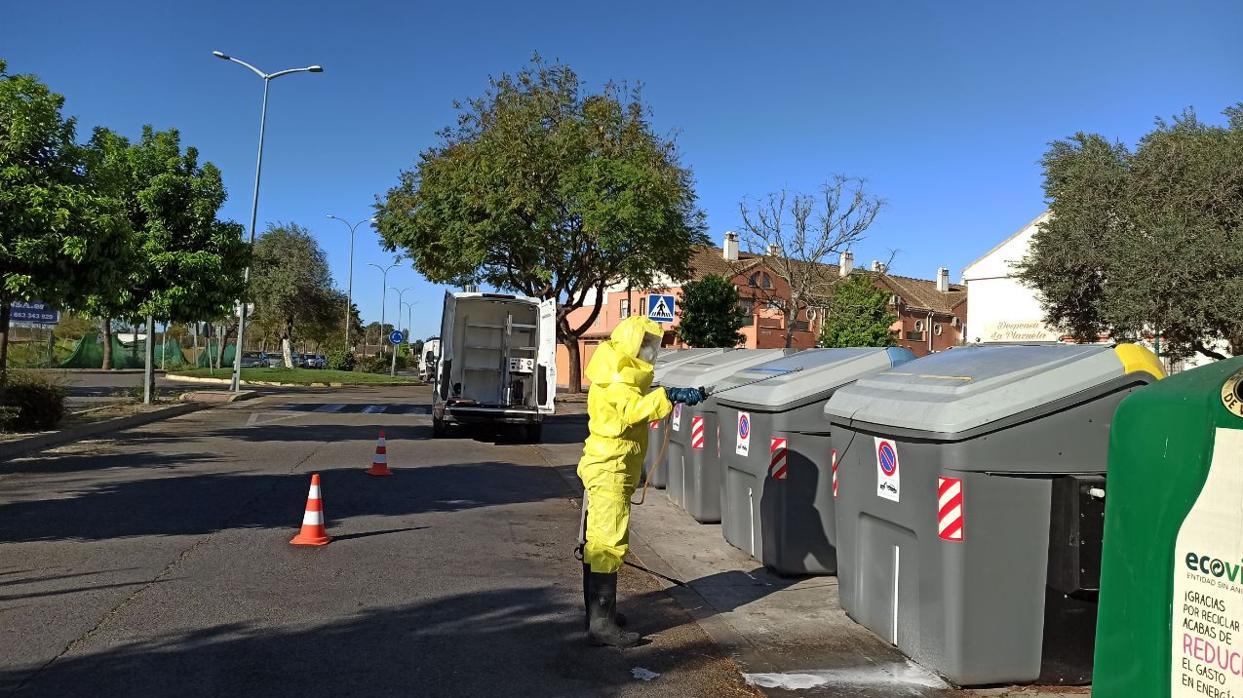 Un operario municipal desinfecta varios contenedores en una calle de Coria del Río