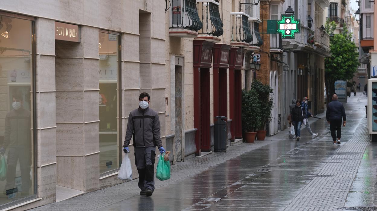 Un ciudadano tras hacer la compra, protegido con mascarilla y guantes.