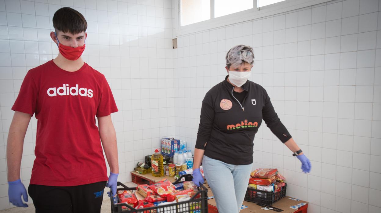 Dos voluntarios portan una caja con alimentos para las familias en situación de emergencia social de Mairena del Aljarafe