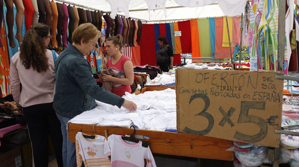 Varias mujeres miran prendas de vestir en un puesto de mercadillo de Cádiz.