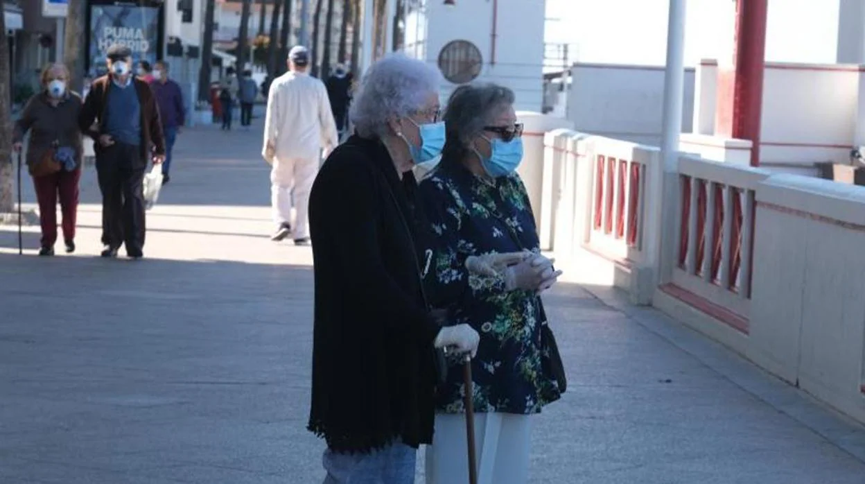 Dos señoras mayores en el paseo marítimo de Cádiz en la franja matinal para el paseo de mayores de 70 años.