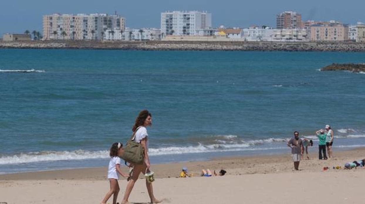 Una madre y su hija pasean por la playa en Cádiz.