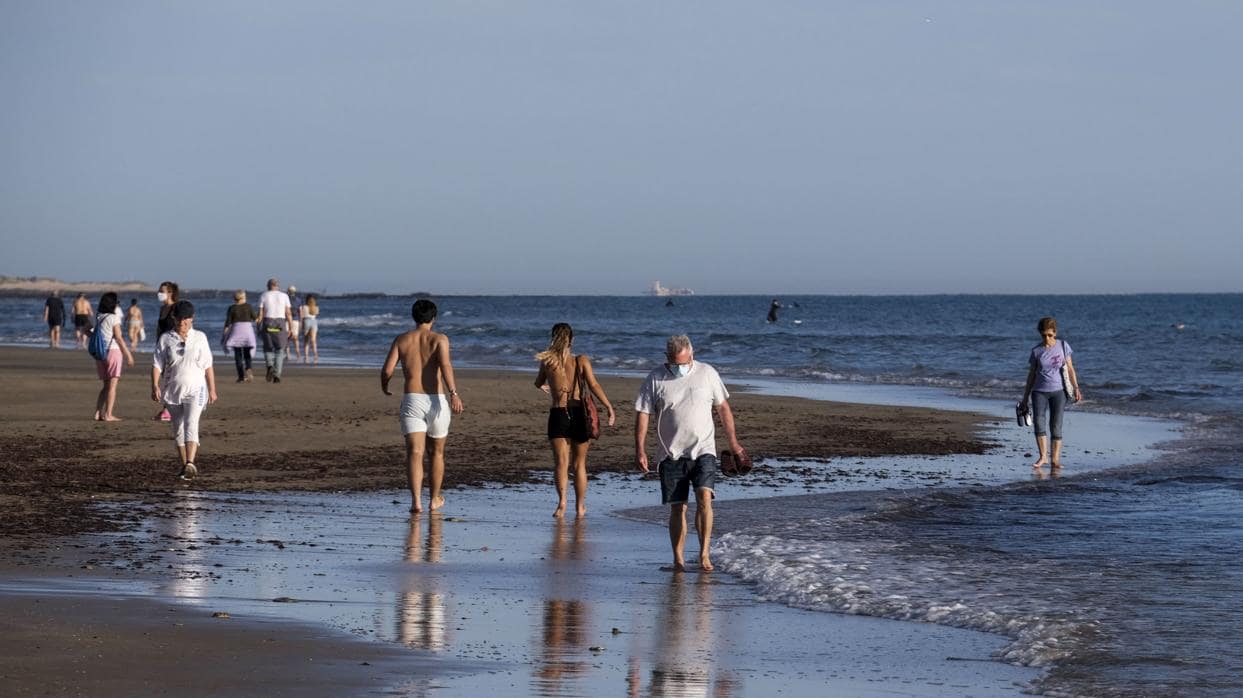 Personas caminando por la orilla en una playa de Cádiz capital.