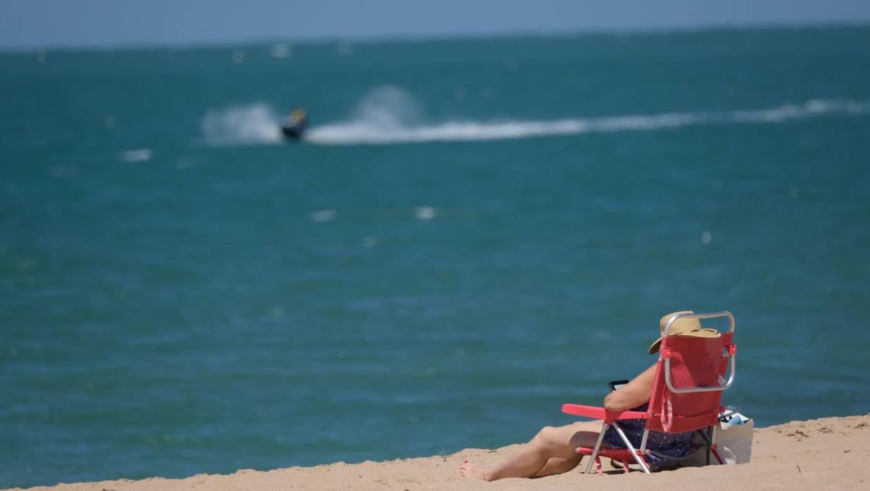 Una señora disfruta de la playa de Rota en el puente festivo de Corpus.