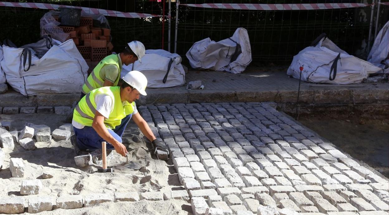 Trabajadores de la construcción adoquinan una calle de Cádiz.