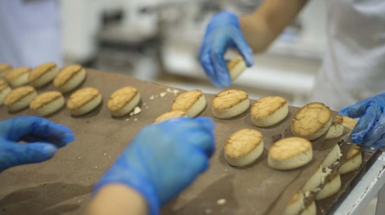 Dos trabajadoras recogen los mantecados de una bandeja en una fábrica de Estepa