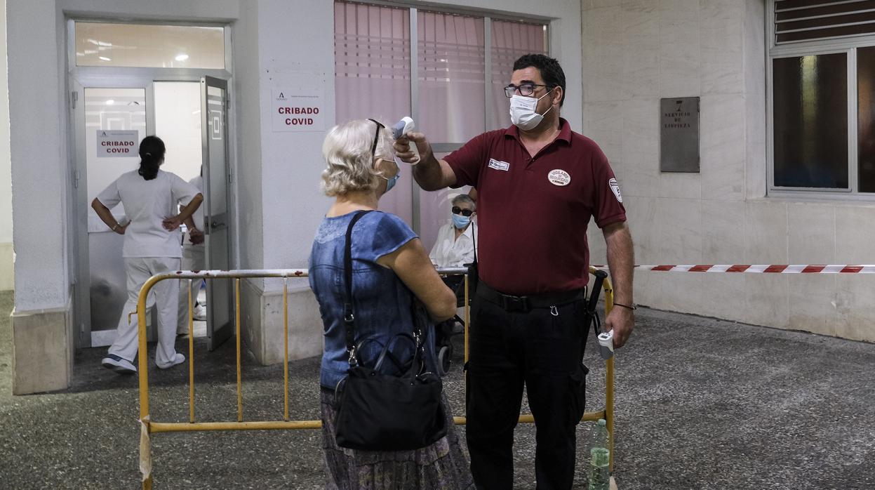 Un seguridad del hospital Puerta del Mar toma la temperatura en la entrada del centro.