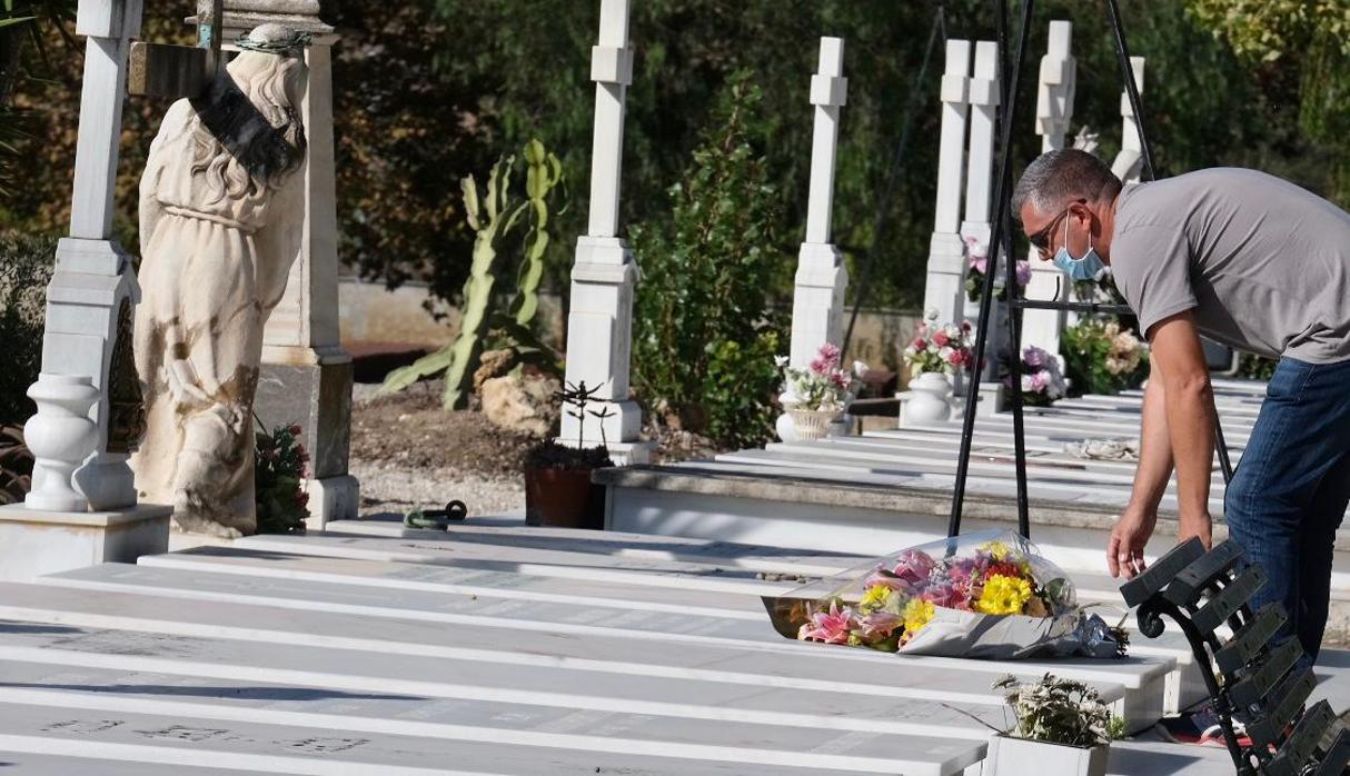 Un hombre depositando unas flores en una tumba en el Cementerio Mancomunado.