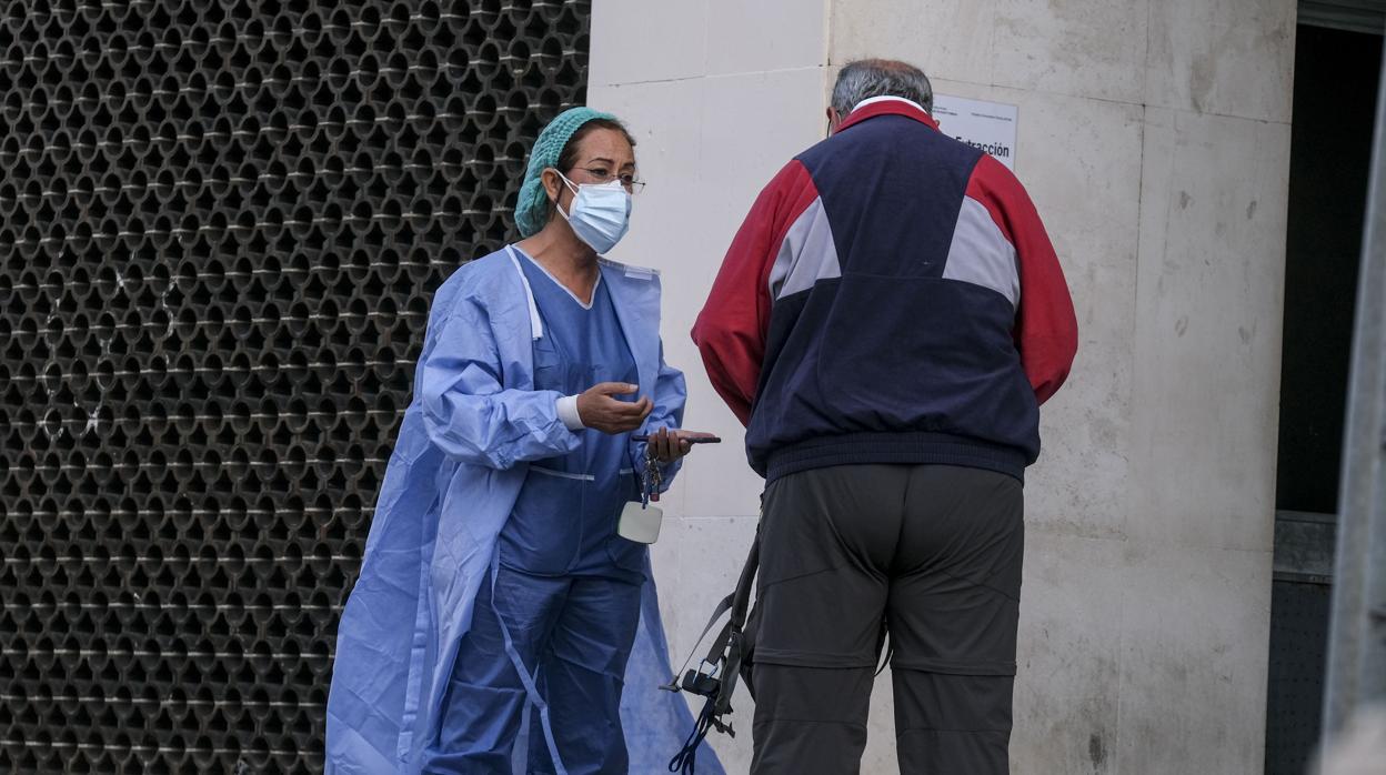 Una sanitaria junto a un paciente, en la entrada del Hospital Puerta del Mar.